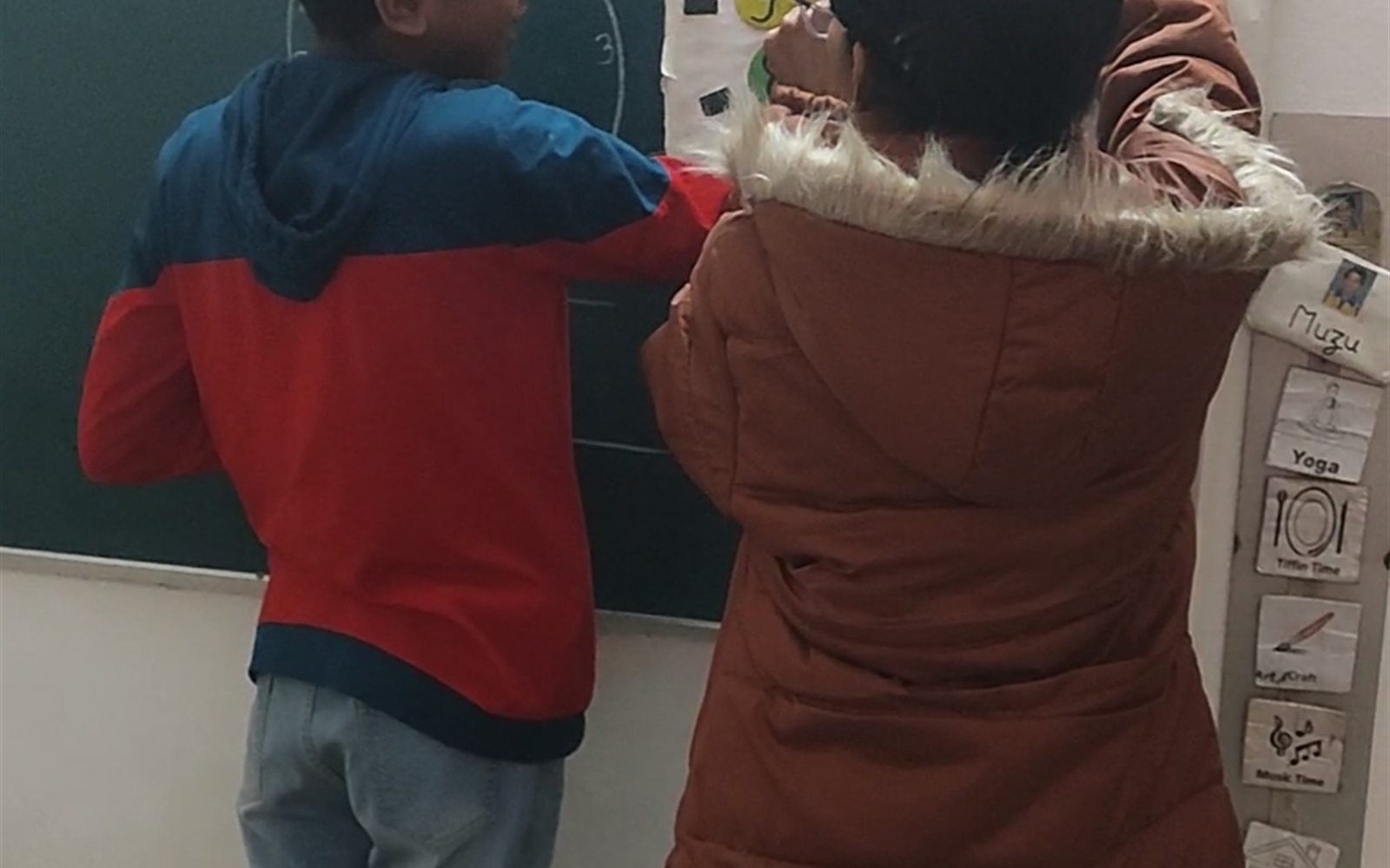 Older student and teacher working on a classroom learning board
