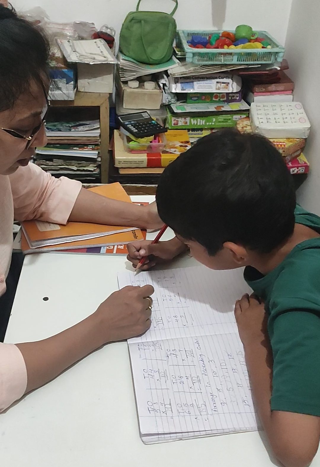 A special educator helping an older student with handwritten math work at ArambH